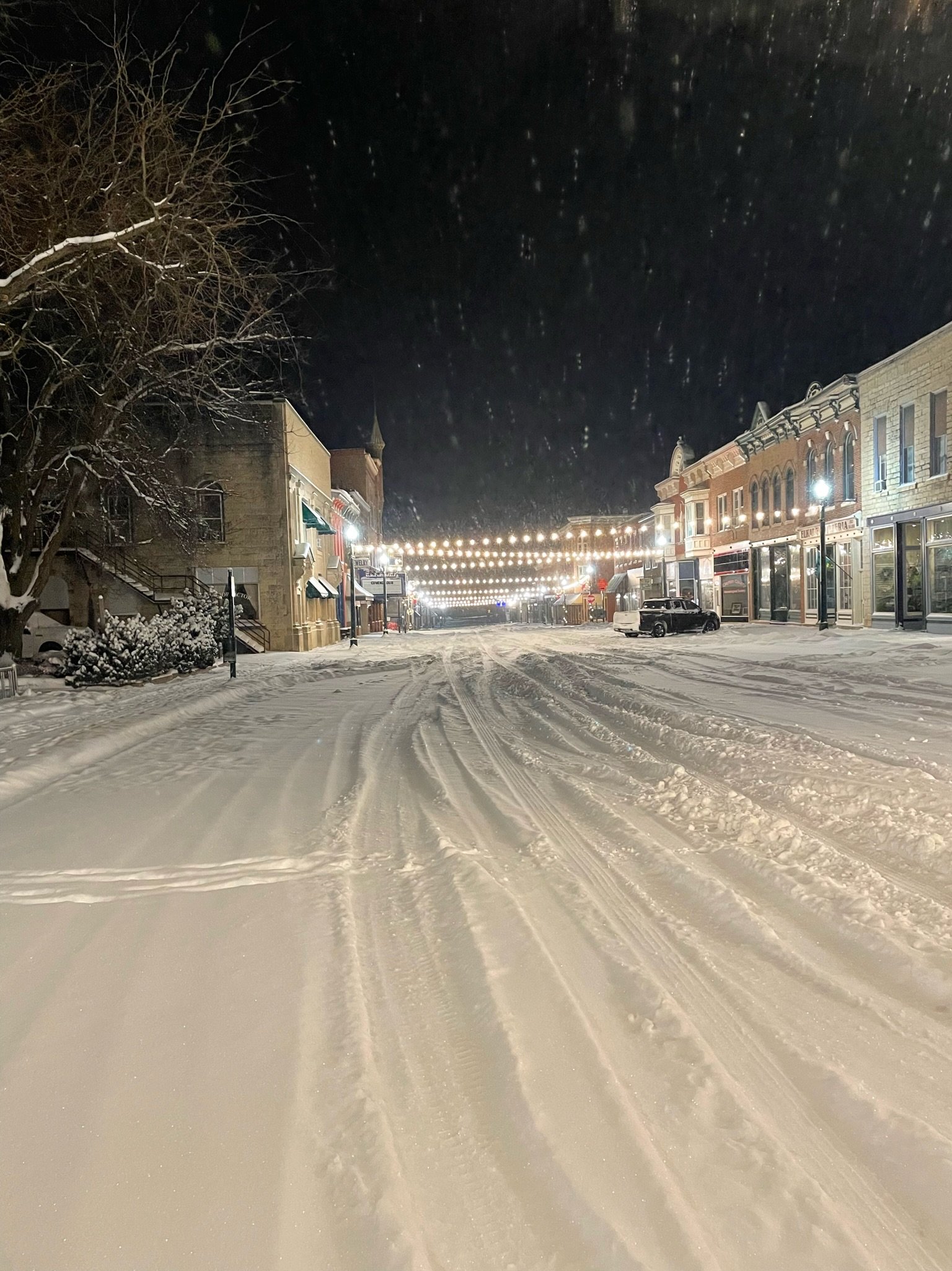 Main Street Elkader at night in the snow, under string lights