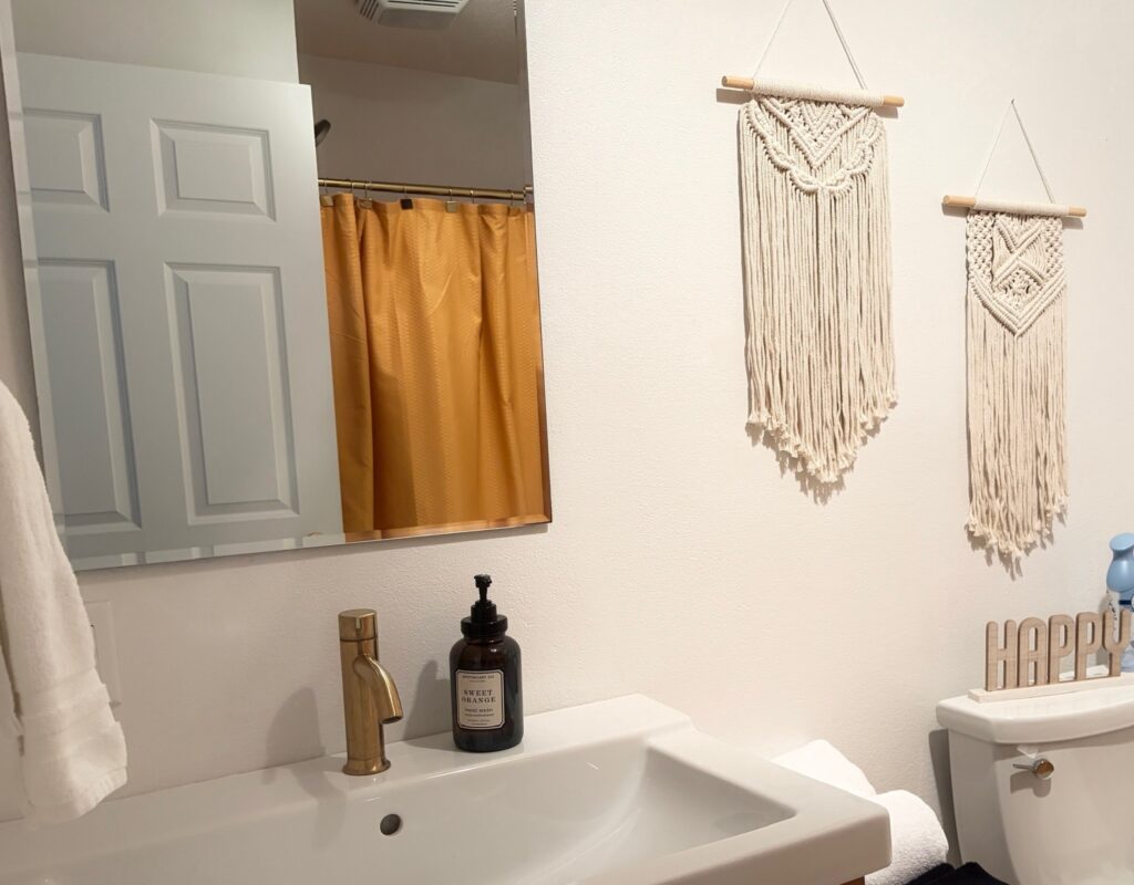 Suite A bathroom with brass fixtures, macramé wall hangings and a shower